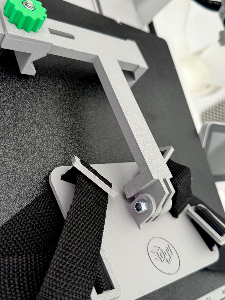 Staffa regolabile grigia progettata in CAD e stampata in 3D, con cinghia nera, snodo bullonato e pomello verde